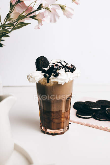 Sweet yummy frappe drink with chocolate cookies on whipped cream in light kitchen — Stock Photo