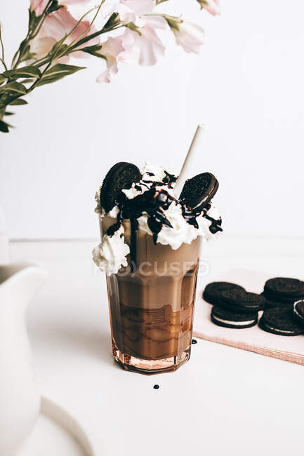 Sweet yummy frappe drink with chocolate cookies on whipped cream in light kitchen — Stock Photo