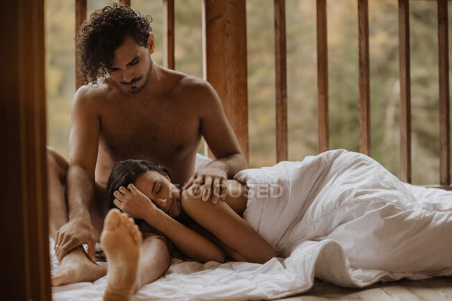 Mulher relaxada deitada dormindo em pernas de namorados em cobertor acolhedor macio no terraço da casa de campo de madeira contra a floresta caduca no outono — Fotografia de Stock