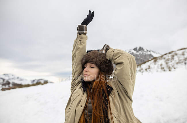 Молодая внимательная туристка с закрытыми глазами дышит против горы во время поездки в Астурию зимой — стоковое фото