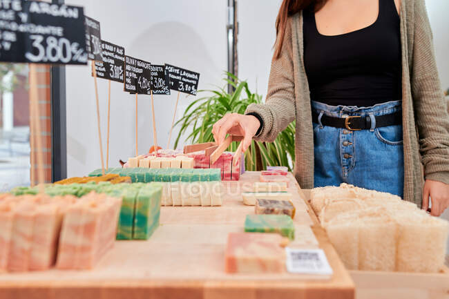 Crop anonymous female buyer picking soap made of natural ingredients while shopping in shop with eco friendly products — Stock Photo