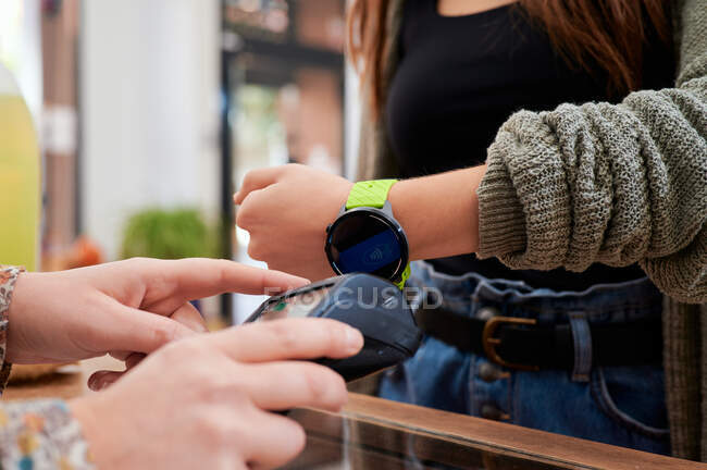 Beschneiden gesichtslose Kundin mit Gadget für kontaktloses Bezahlen auf drahtlosem Terminal im Geschäft — Stockfoto
