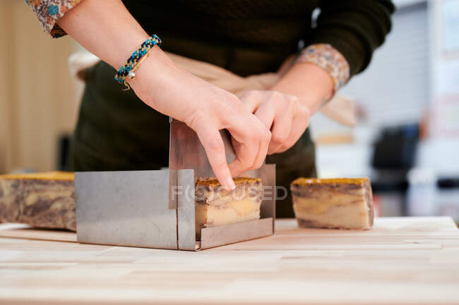 Cortar anônimo vendedor feminino cortando sabão orgânico para cliente em loja ecológica — Fotografia de Stock