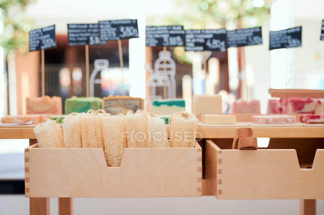 Varios jabón hecho a mano de colores con pinzas y etiquetas de precios colocados en la mesa de madera en eco tienda - foto de stock