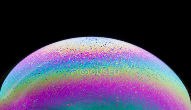 Panoramic view of closeup bubble textured backdrop representing colorful planet with wavy lines on round shaped surface on black background — Stock Photo