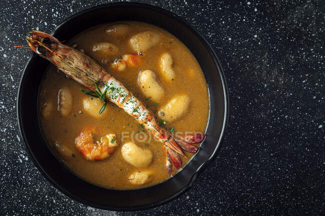 From above of appetizing cream soup with white beans and langoustines served in bowl and placed on marble tabletop in kitchen — Stock Photo