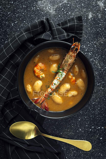 From above of appetizing cream soup with white beans and langoustines served in bowl and placed on marble tabletop near napkin in kitchen — Stock Photo