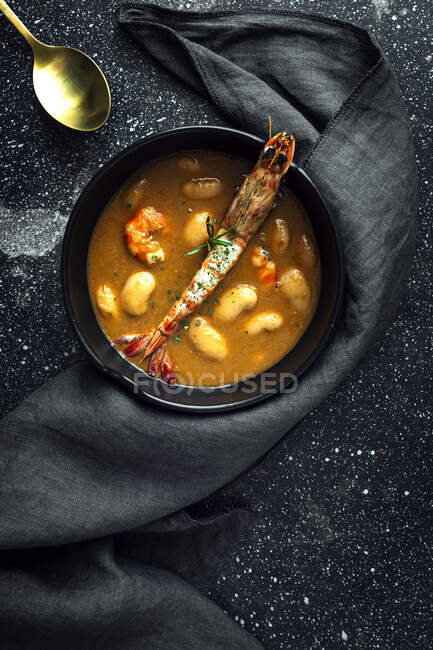 De cima de sopa de creme apetitoso com feijão branco e langoustines servido em tigela e colocado em mesa de mármore perto de guardanapo na cozinha — Fotografia de Stock