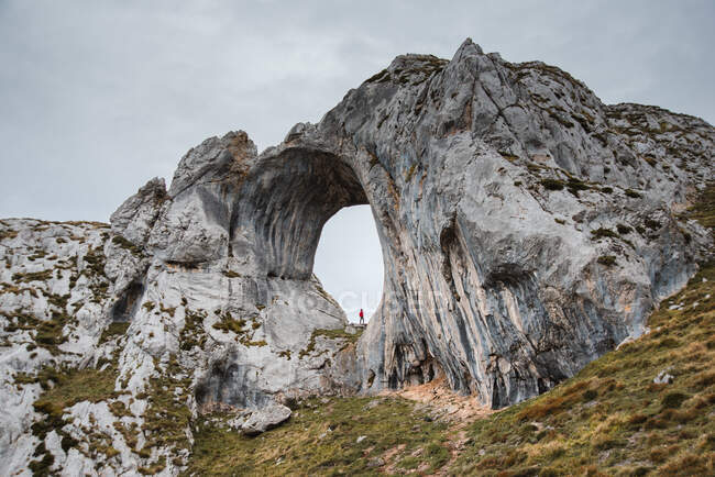 Voyageur éloigné debout dans un grand trou de formation rocheuse rugueuse dans les Asturies en Espagne par temps nuageux — Photo de stock