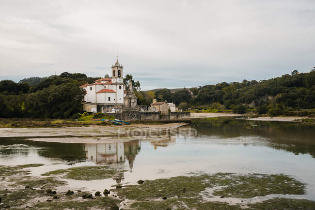 Paesaggio pittoresco di Parrocchia bianca di Nostra Signora Addolorata sulla riva tranquilla su tempo coperto nelle Asturie Spagna — Foto stock