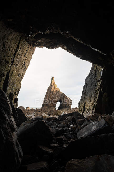 De piedra áspera cueva paisaje de roca aguda severa con agujero situado en pedregoso amplio terreno a la luz del día - foto de stock