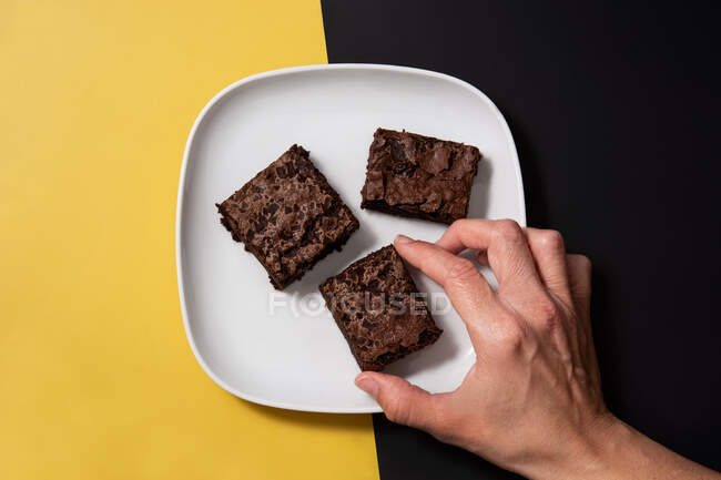 Pieces of fresh brownie on black and yellow background — Stock Photo