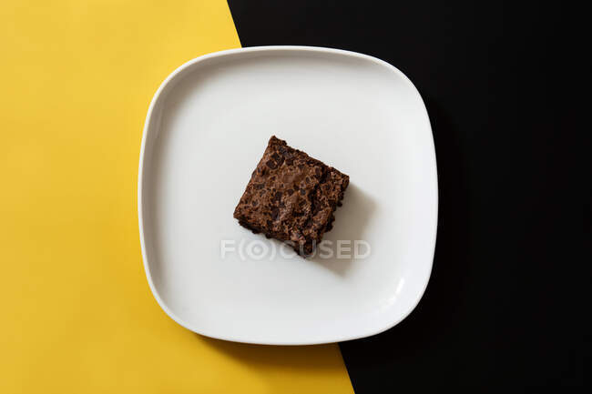 Stück frischer Brownie auf schwarzem und gelbem Hintergrund — Stockfoto