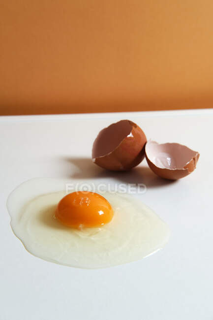 Desde arriba de huevo fresco de pollo crudo colocado sobre fondo blanco en estudio brillante - foto de stock