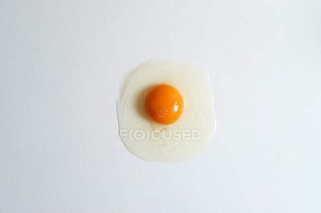 Vista superior de huevo fresco de pollo crudo colocado sobre fondo blanco en estudio brillante - foto de stock