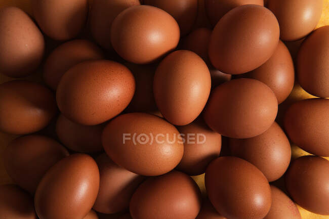 D'en haut de plein cadre fond de tas d'œufs de poulet brun crus — Photo de stock