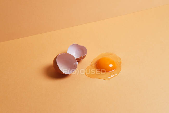 Desde arriba de huevo fresco de pollo crudo colocado sobre fondo naranja en estudio brillante - foto de stock