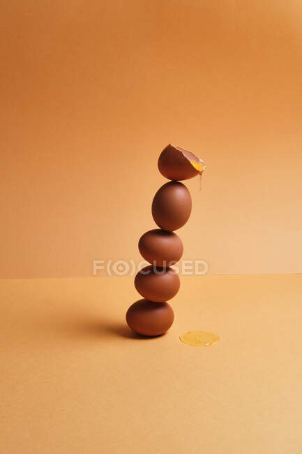 Stapel brauner frischer Eier balancieren auf dem Tisch auf Pfirsichhintergrund im Atelier — Stockfoto