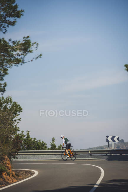 Ganzkörper junger Sportler in Aktivkleidung und Helm beim Fahrradfahren auf asphaltierter Straße an sonnigen Tagen — Stockfoto