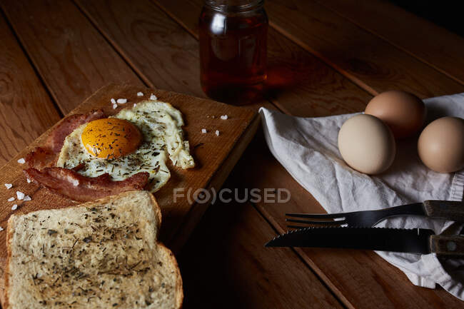 D'en haut de savoureux œufs frits maison au jaune et au bacon assaisonnés d'épices et de sel — Photo de stock