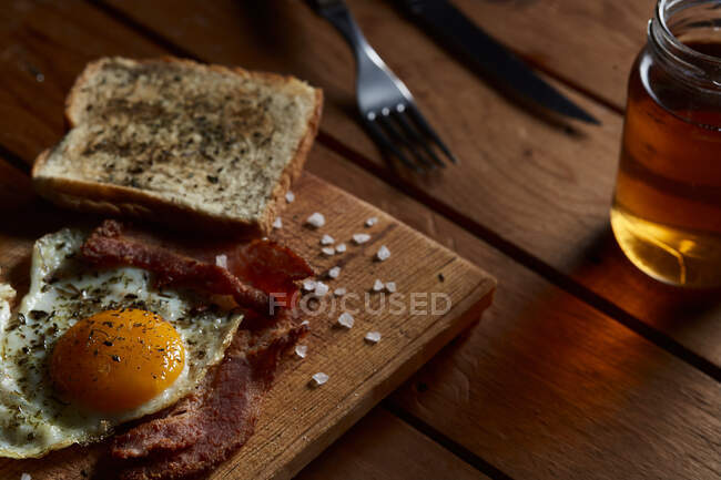 De cima de ovos fritos caseiros saborosos com gema de ovo e bacon temperado com especiarias e sal — Fotografia de Stock