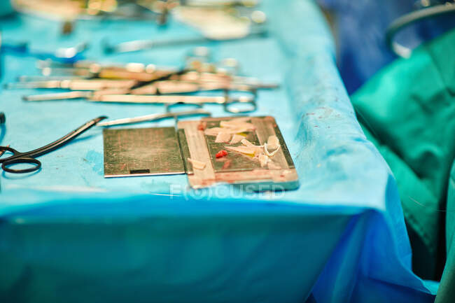 Высокий угол различных хирургических ножниц и пинцета, разбросанных по стерильному полю возле операционного стола — стоковое фото