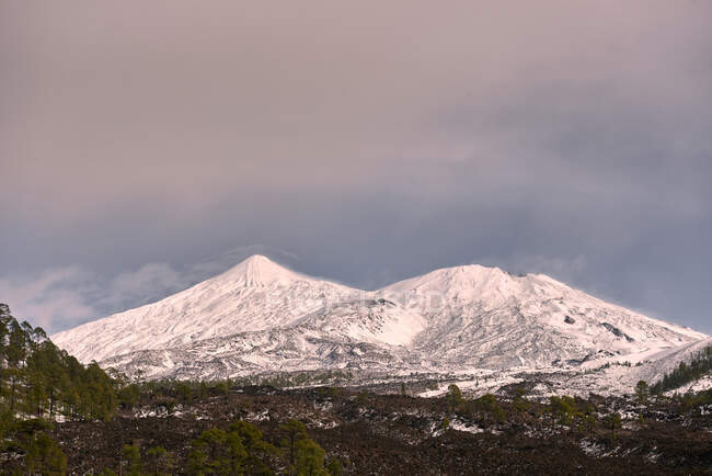 Мальовничі пейзажі гірського хребта зі схилами, покритими товстим шаром снігу, розташованим на величезній нерівній долині під блакитним небом — стокове фото