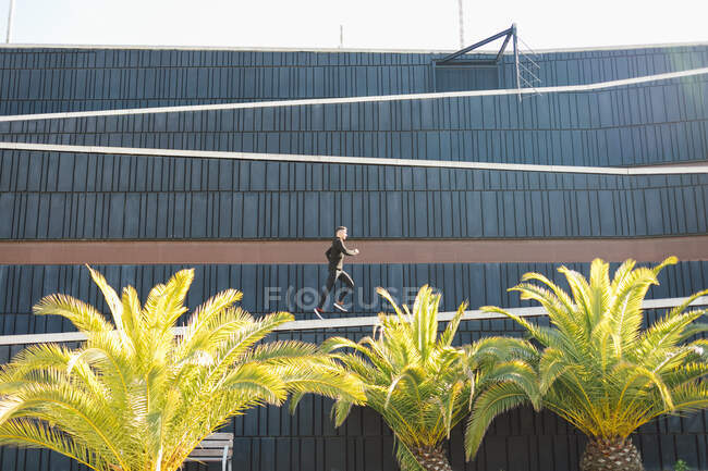 Мужчина спортивного телосложения в спортивном костюме бегает по пешеходной дорожке на творческой стене в солнечный день — стоковое фото