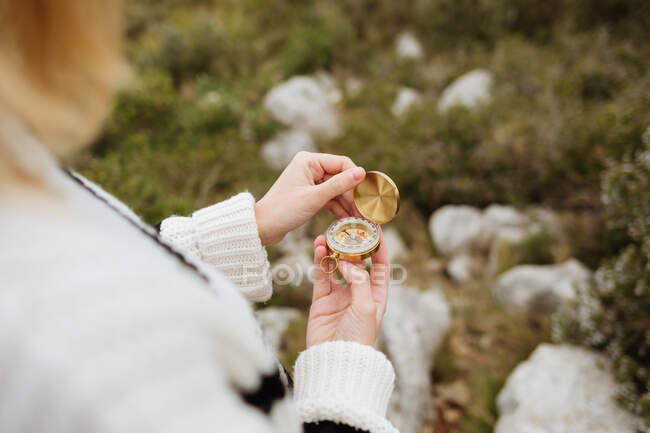 Зверху врожаю анонімні жінки-туристки використовують компас на горі з грубими каменями в денне світло — стокове фото