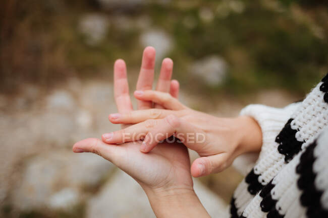Crop anonymous female tourist in knitted sweater with ornament showing friendship gesture on mountain in daylight — Stock Photo