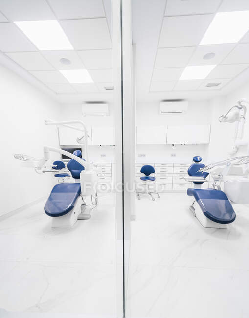 Intérieur de clinique dentaire contemporaine bien rangée avec chaise bleue et mobilier blanc équipé d'une machine dentaire moderne et d'instruments — Photo de stock