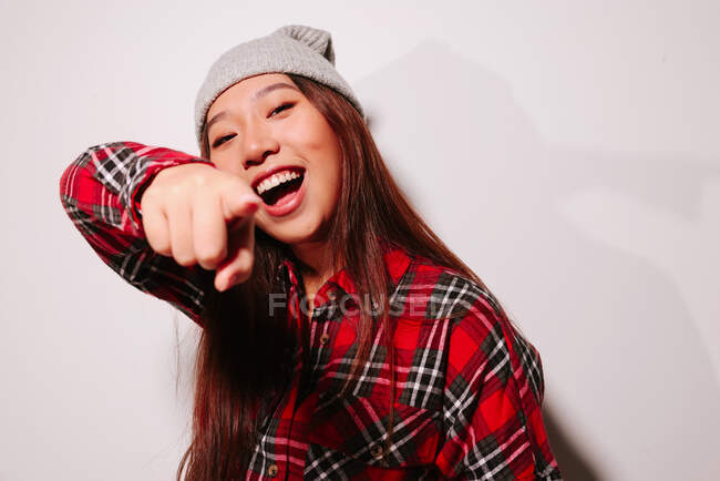 Крупный план портрета веселой азиатской молодой женщины, указывающей пальцем на камеру — стоковое фото
