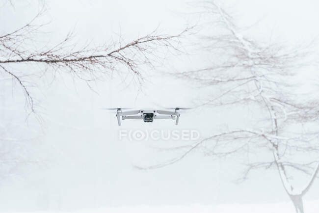 VANT branco contemporâneo sobrevoando a clareira nevada em florestas congeladas de inverno à luz do dia — Fotografia de Stock