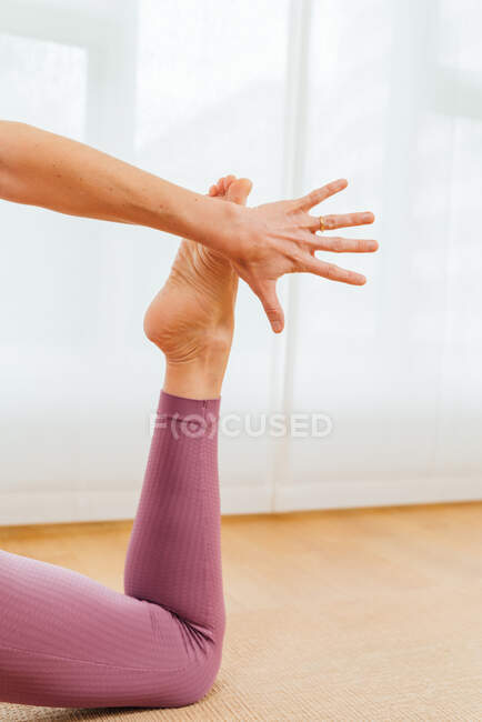 Vista de cerca de la mano y el pie de la mujer realizando Horizon Lunge asana durante la sesión de yoga en el estudio - foto de stock