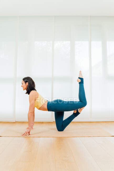 Side view full body of focused barefoot sportswoman stretching body and improving endurance during yoga practice — Stock Photo