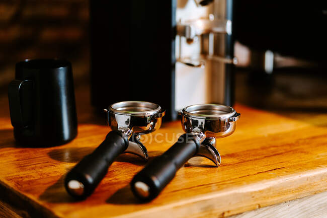 Portafilters placed on wooden table in cafe — Stock Photo