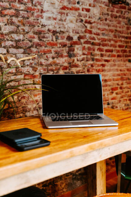 Moderno netbook colocado en el mostrador de madera en la cafetería con interior en estilo loft - foto de stock