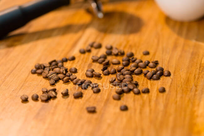 Les grains de café et les portafilters placés sur une table en bois avec tasse vide dans le café — Photo de stock