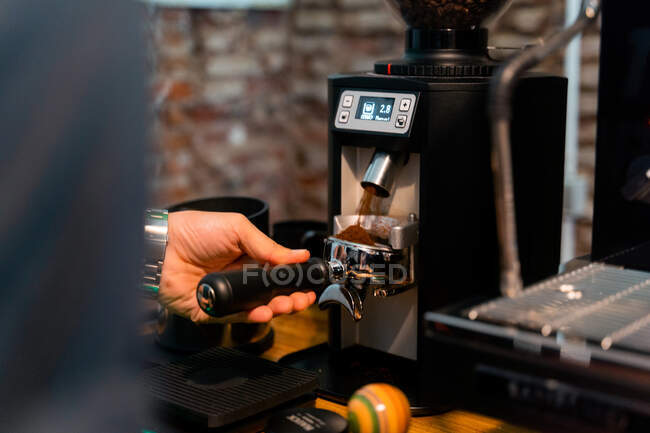 Обрізати невпізнаваний бариста пресування кави в портативному фільтрі з тампоном під час приготування напою в кафе — стокове фото