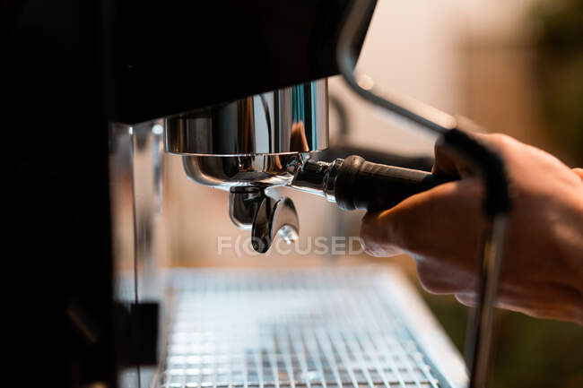 Cultiver barista anonyme en utilisant portafilter dans la machine à café tout en préparant la boisson dans le café — Photo de stock