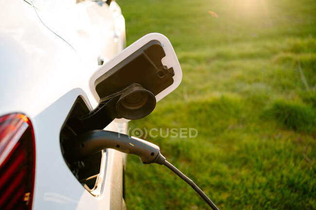 From above of electric ecologic car recharging parked on road near green field on sunny day — Stock Photo