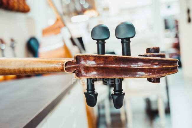 Col de violon fin avec cordes et chevilles accordantes contre mur blanc dans un studio de musique moderne — Photo de stock