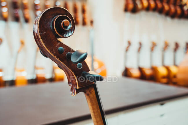 Thin violin neck with strings and tuning pegs against white wall in modern musical studio — Stock Photo