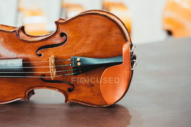 Moderno violino brilhante colocado sobre mesa de madeira gasto em oficina — Fotografia de Stock