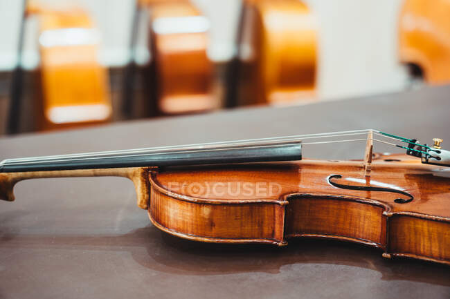 Сучасна блискуча скрипка, розміщена на міцному дерев'яному столі в майстерні — стокове фото