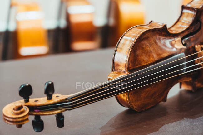 Moderne, glänzende Geige auf schäbigem Holztisch in Werkstatt platziert — Stockfoto