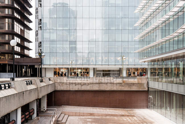 Fachada de construção multiestágio contemporânea com escadas em pavimento e paredes geométricas refletindo a cidade durante o dia — Fotografia de Stock
