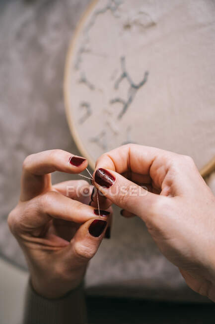 From above crop female with hoop and threads embroidering star constellations while sitting at table in light workshop — Stock Photo
