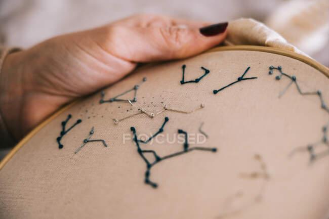 Вид сбоку женщины с обручем и нитками, вышивающими звезду, сидя за столом в легкой мастерской — стоковое фото
