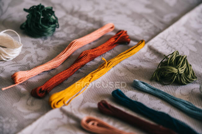 Collection of assorted multicolored mouline threads arranged on white tablecloth for embroidery work in light room — Stock Photo